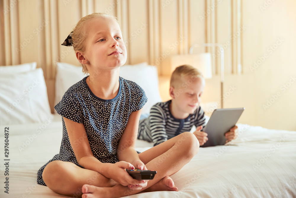 Little girl watching tv with her brother on a bed