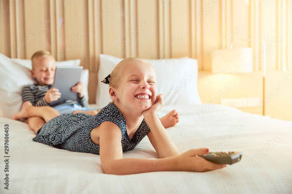 Laughing little girl watching television on a bed