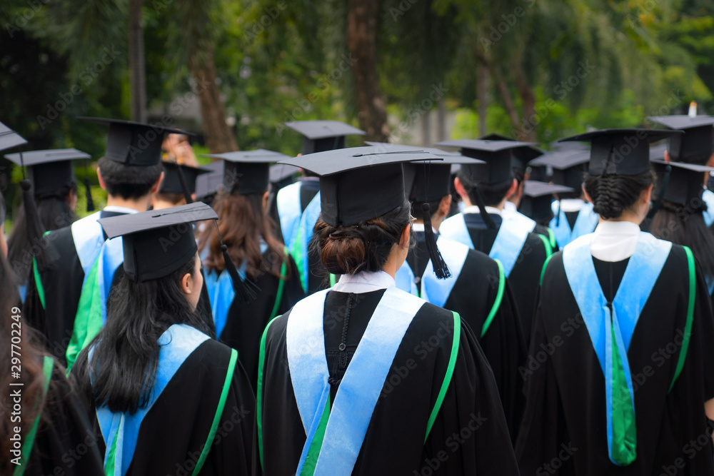 一群穿着黑色礼服的大学毕业生在大学毕业典礼上排队攻读学位的背影