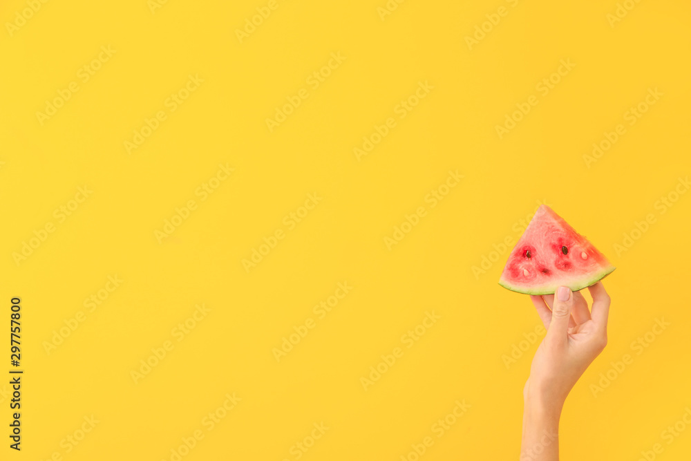 Female hand with piece of juicy watermelon on color background