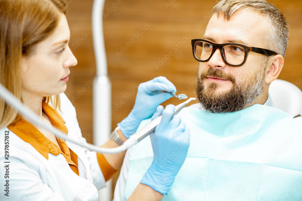 Female dentist and handsome man as a patient during a medical consultation at the dental office