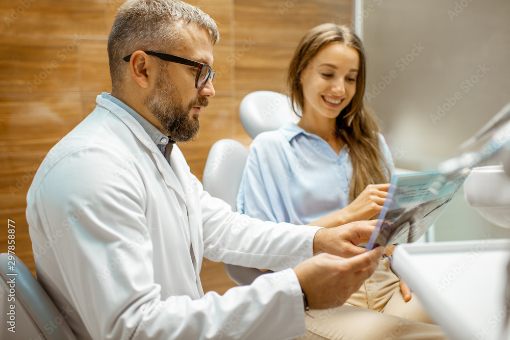 Young patient with senior dentist during a medical consultation at the dental office, doctor showing