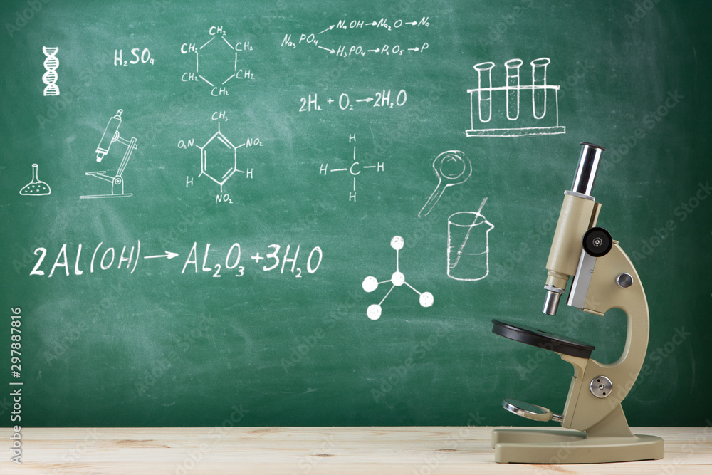 Education concept - microscope on the desk in the auditorium, blackboard background