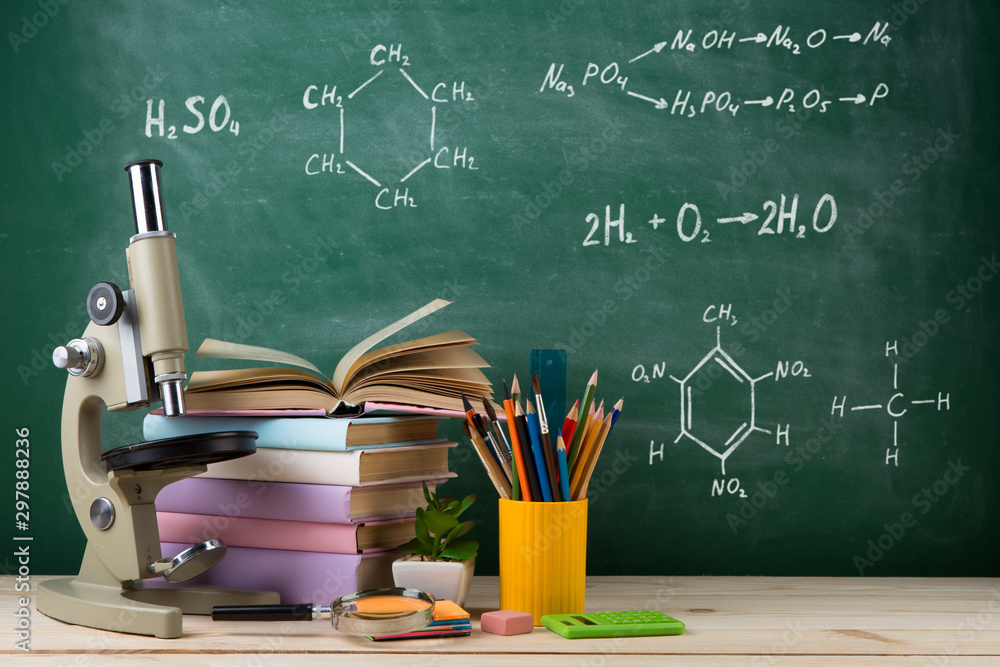 教育与科学概念——教室木桌上的一组彩色书籍和显微镜