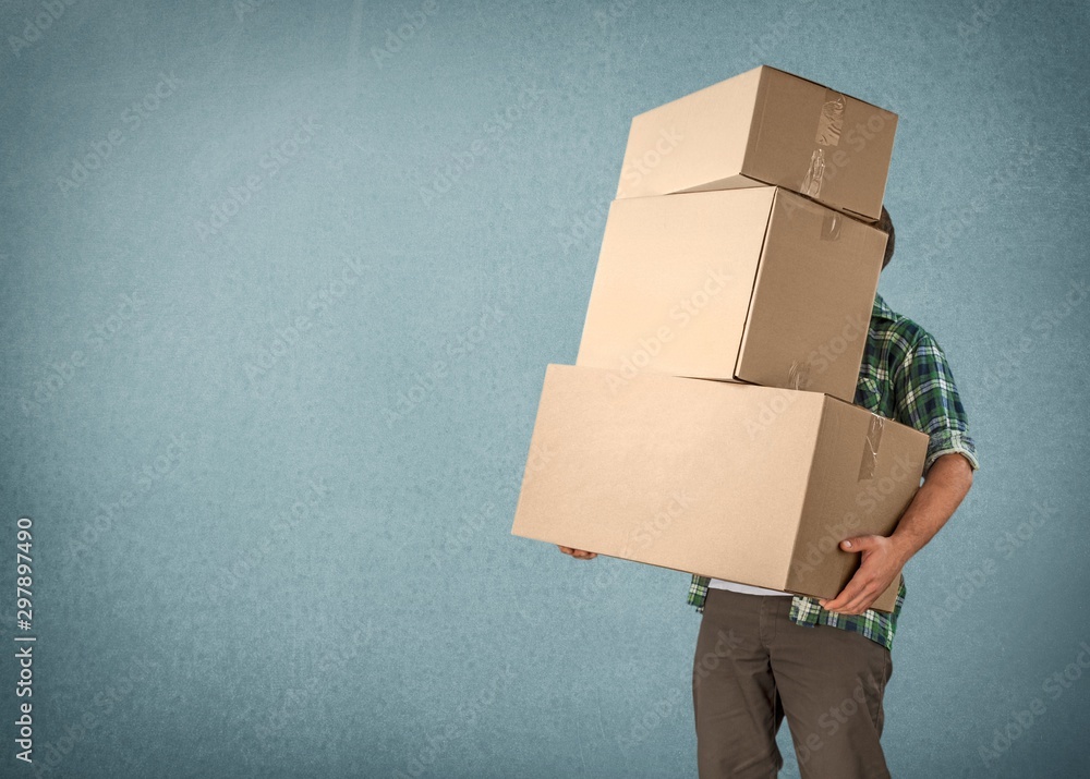 Delivery man carrying stacked boxes in front of face against  background