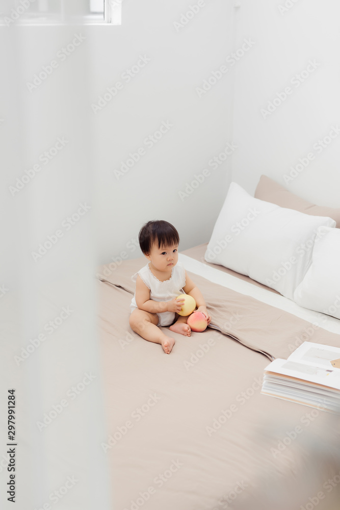 Funny happy toddler girl playing with toy on bed. Kids play at home.