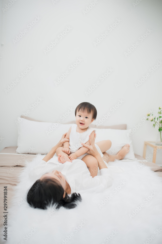 Portrait of mother and child daughter playing having fun together on bed. Kid at home concept.