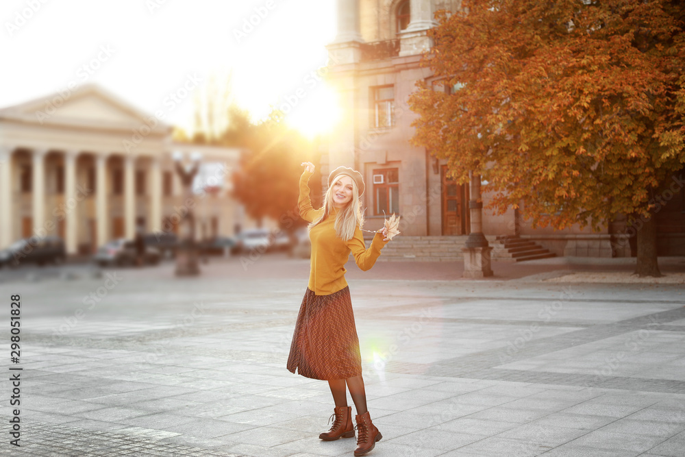 Beautiful young woman in city on autumn day