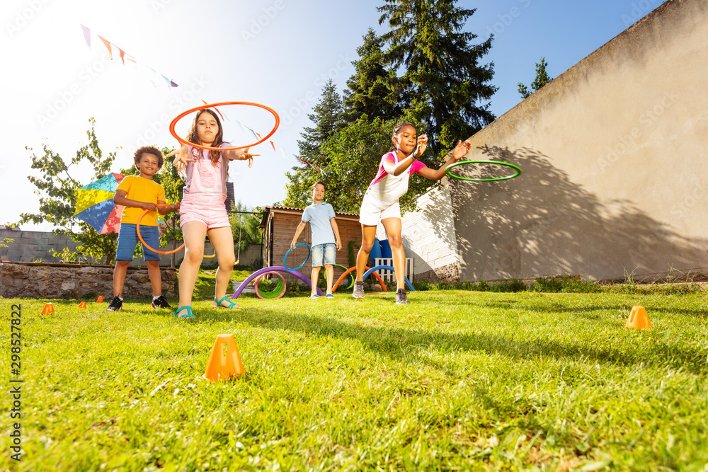 Group of kids throw hula rings to the target