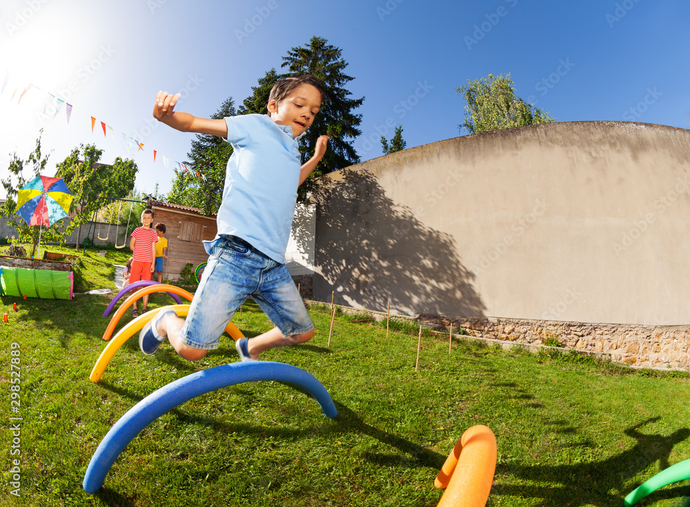 Happy boy play competitive game jump over barriers