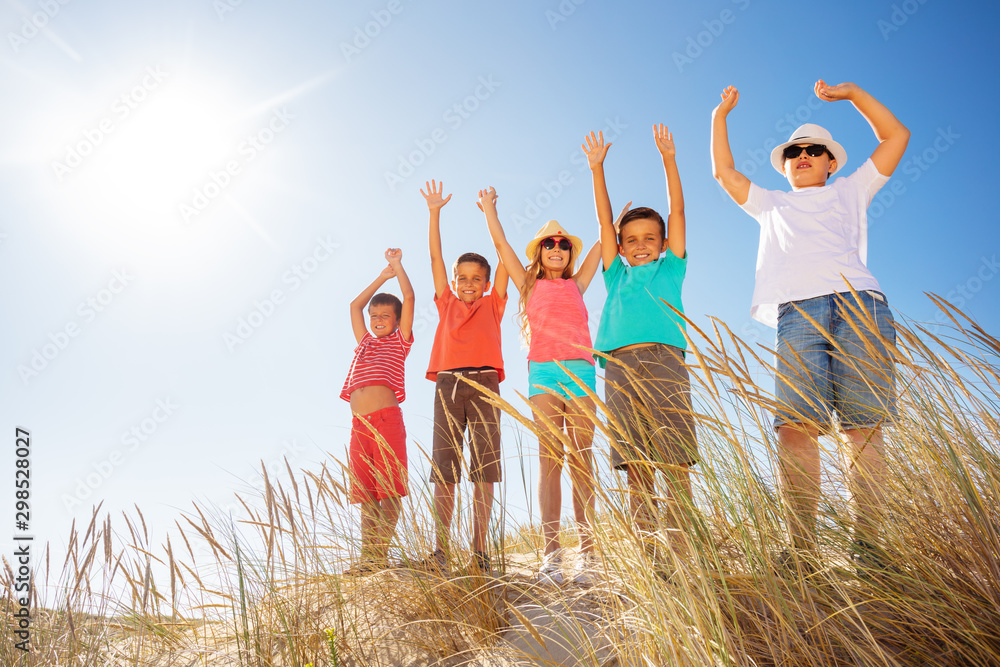 Many kids on the sand beach happy lift hands up