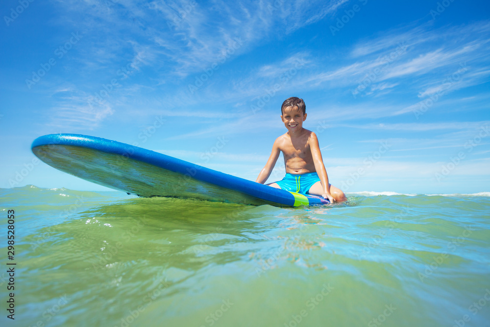 Little boy sit on surfboard waiting for the wave