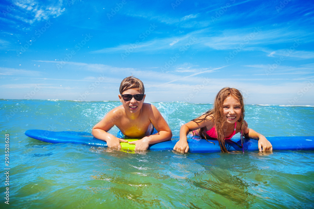 Boy and girl swim on surfing board in sea water