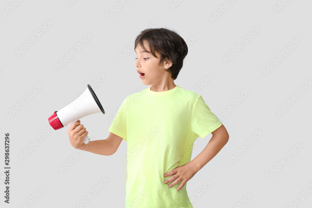 Surprised little boy with megaphone on light background