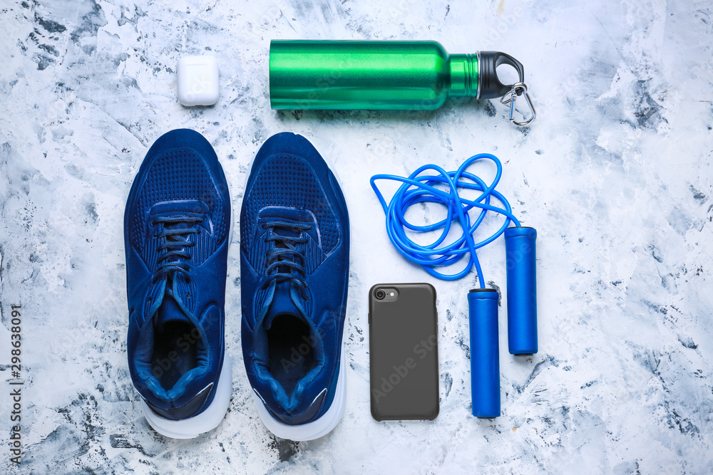 Sports water bottle, shoes, mobile phone and jumping rope on light background