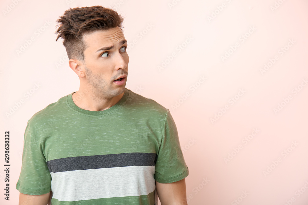 Shocked young man on color background