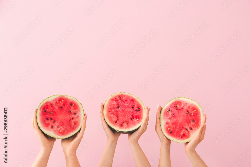 Female hands with halves of ripe watermelon on color background