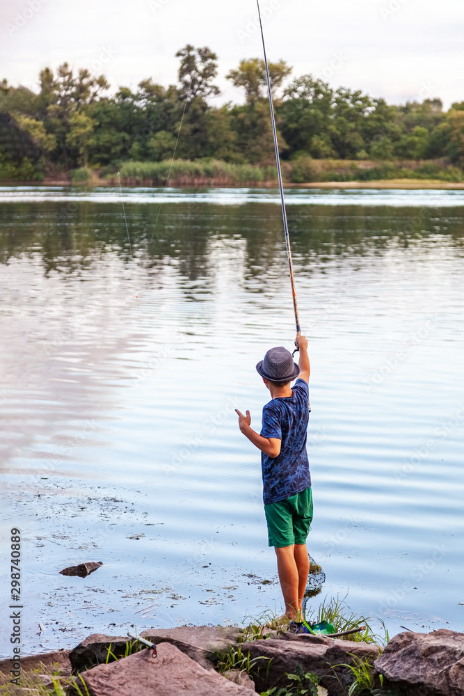 Boy with a fishing rod catches a fish