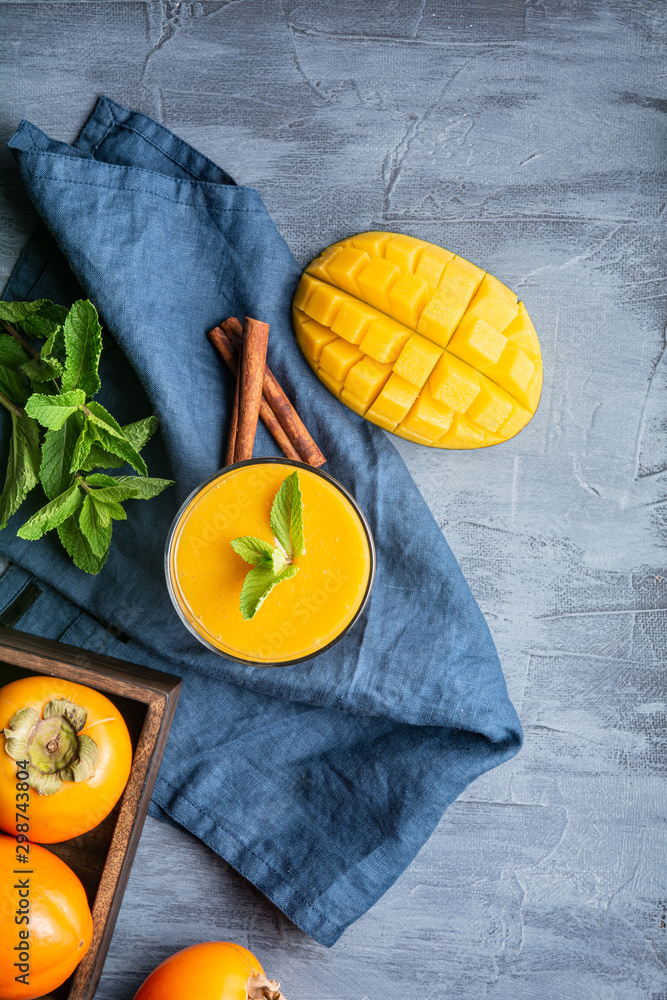 Spicy mango and persimmon smoothie with ginger and cinnamon in a glass jar for immunity and digestio