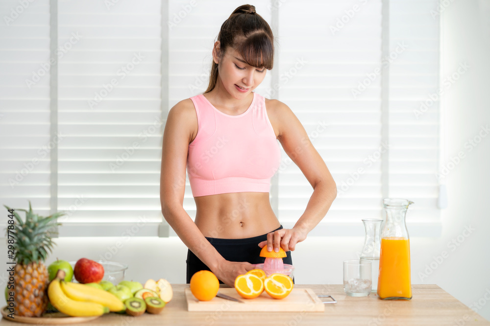 Asian girl make an orange juice by hand at home after finished exercise