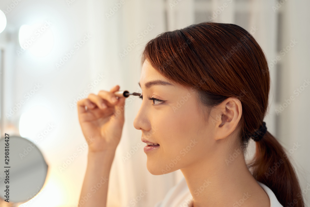 Closeup Of Beautiful Asian Woman Putting Black Mascara On Eyelashes. Beauty Cosmetics.