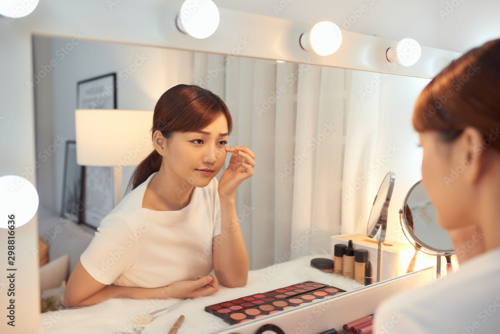 Young Asian woman taking care of her skin while looking in the morror