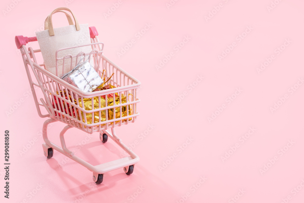 Annual sale shopping season concept - mini pink shop cart trolley full of paper bag gift isolated on