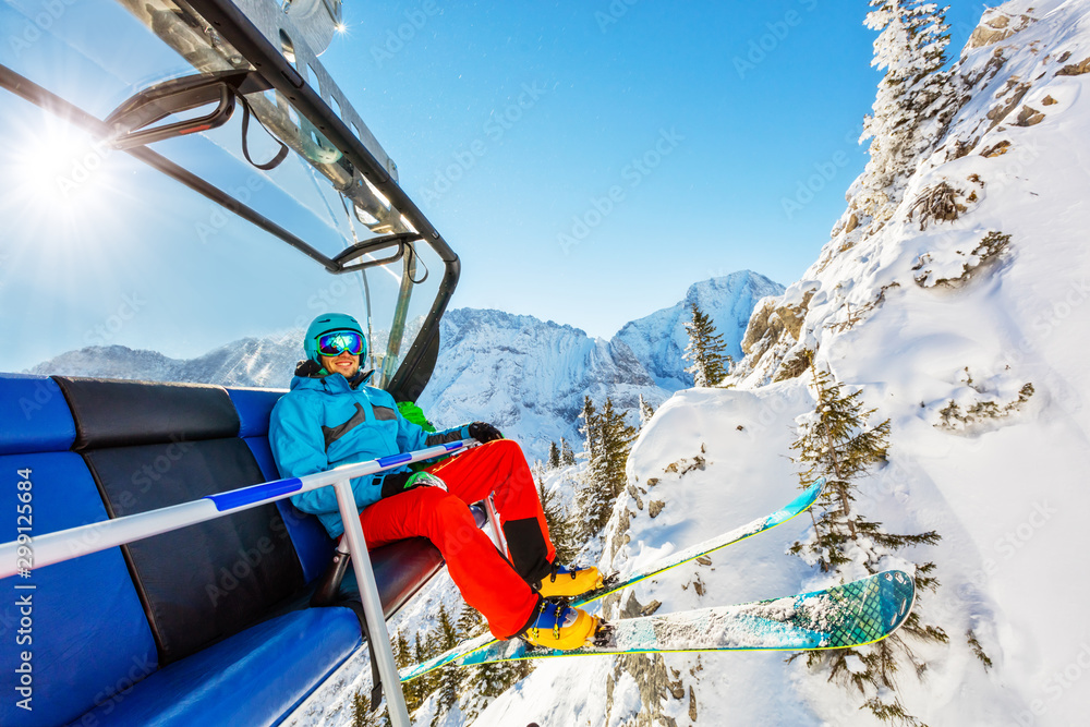 Skier sitting at ski lift in high mountains during sunny day