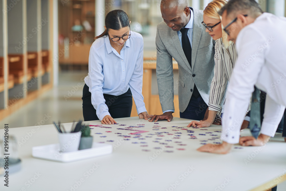 Diverse businesspeople solving a jigsaw puzzle together in an of