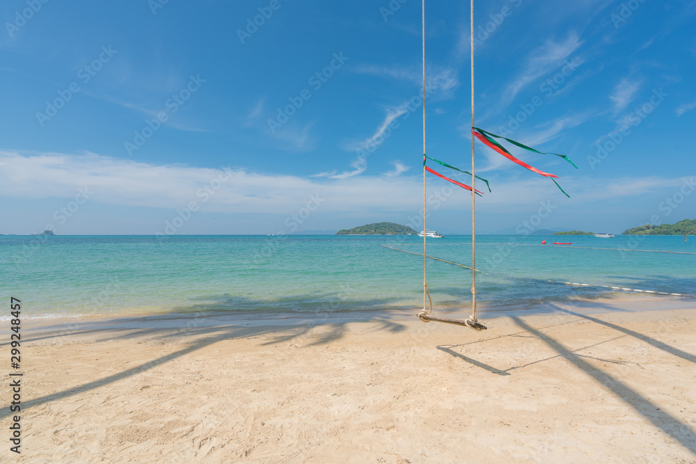 在海水清澈的夏季海滩上，从椰子树上荡秋千，快艇驶入