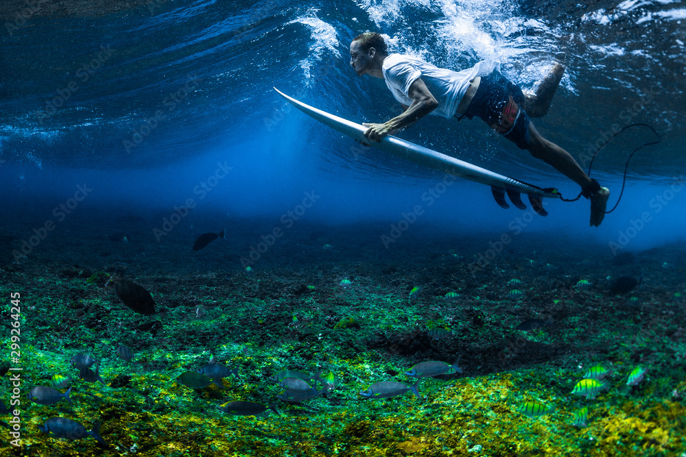 冲浪者用冲浪板在海浪下潜水。水下拍摄有生动的珊瑚礁和大量的f