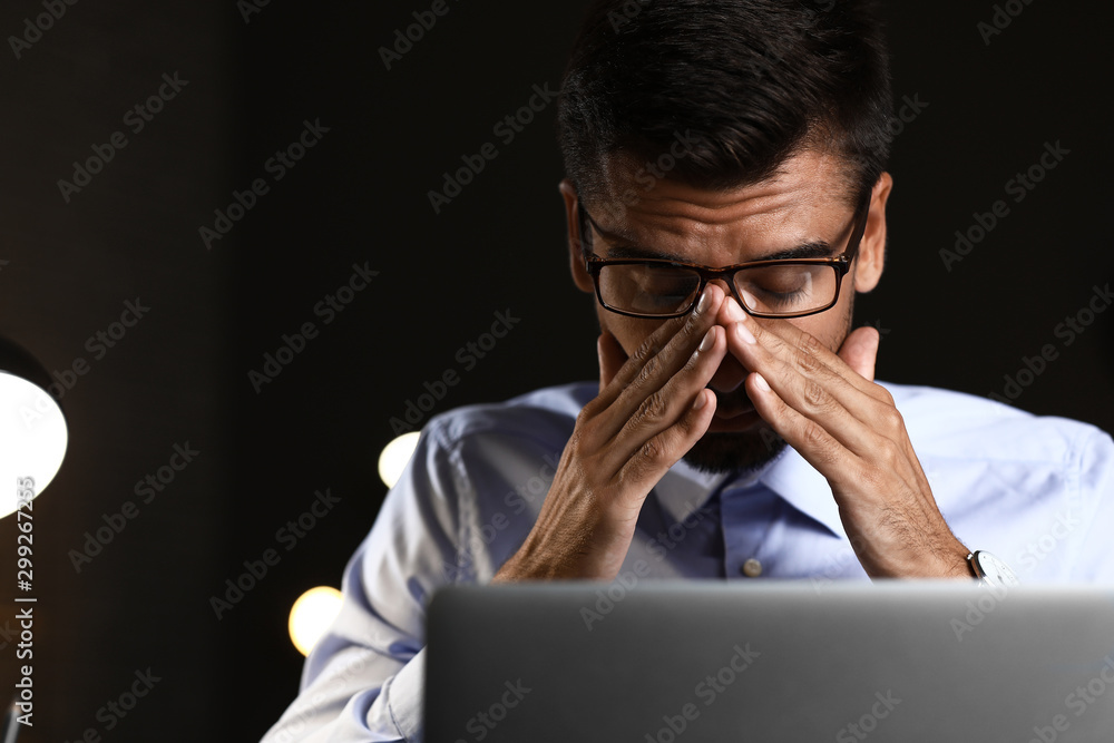 Tired businessman trying to meet deadline in office late in evening