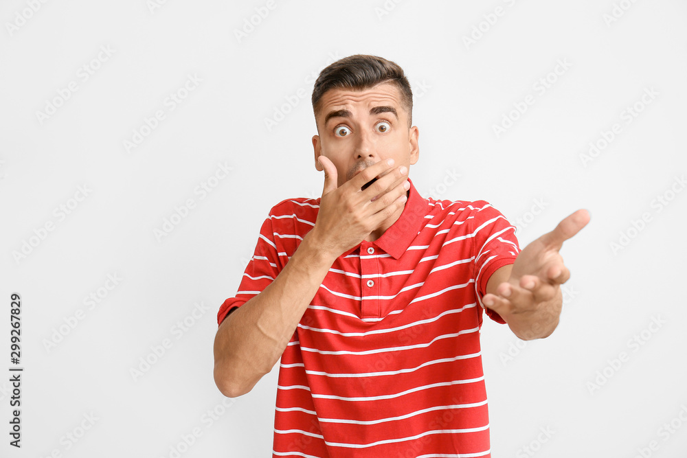 Shocked young man on light background