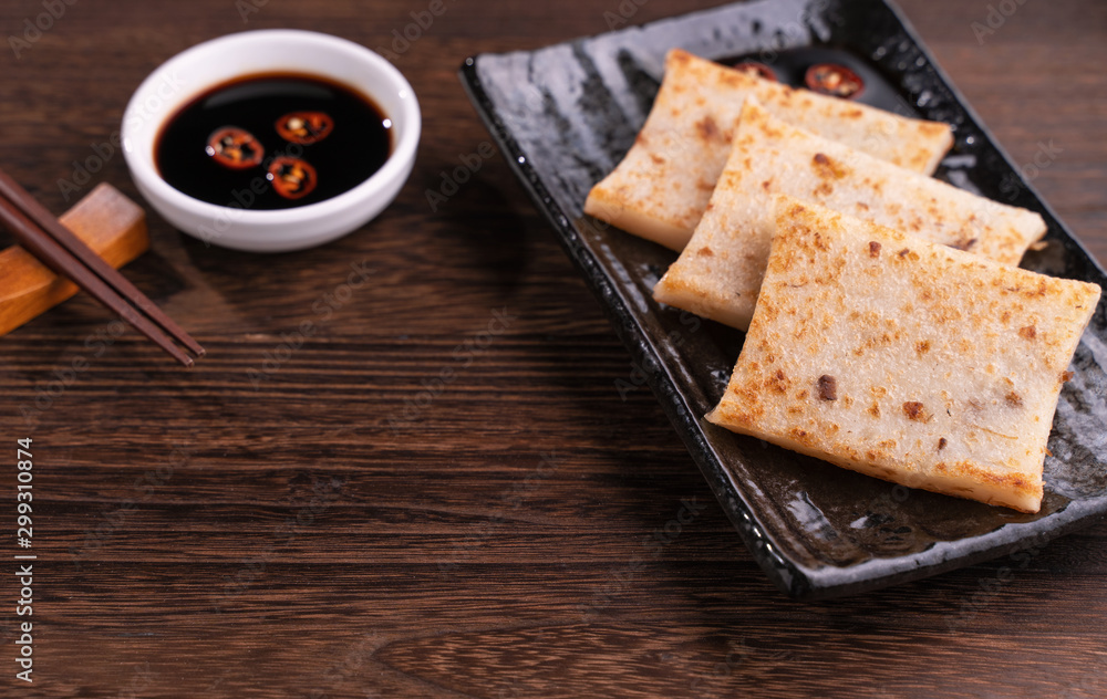 Delicious turnip cake, Chinese traditional local dish radish cake in restaurant with soy sauce and c