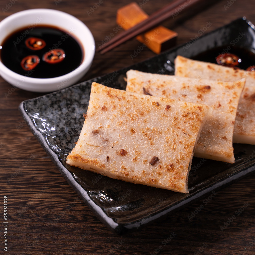 Delicious turnip cake, Chinese traditional local dish radish cake in restaurant with soy sauce and c