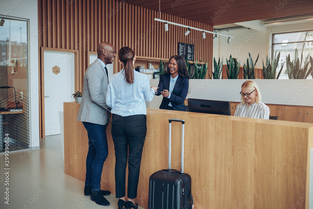 Two smiling guests giving their reservation infomation to hotel