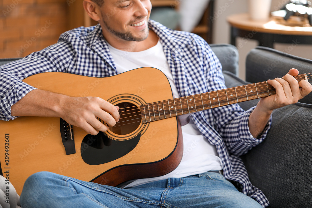 Handsome man playing guitar at home