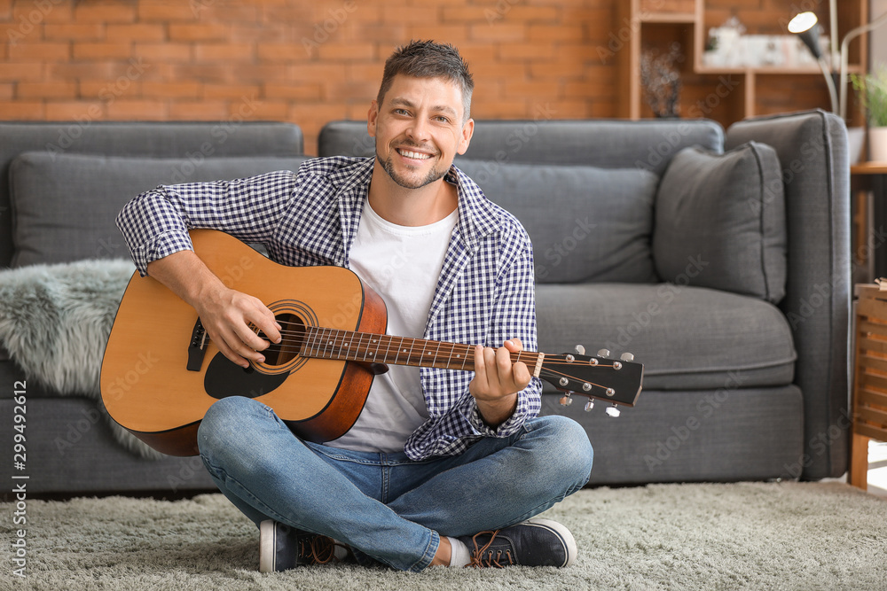 Handsome man playing guitar at home