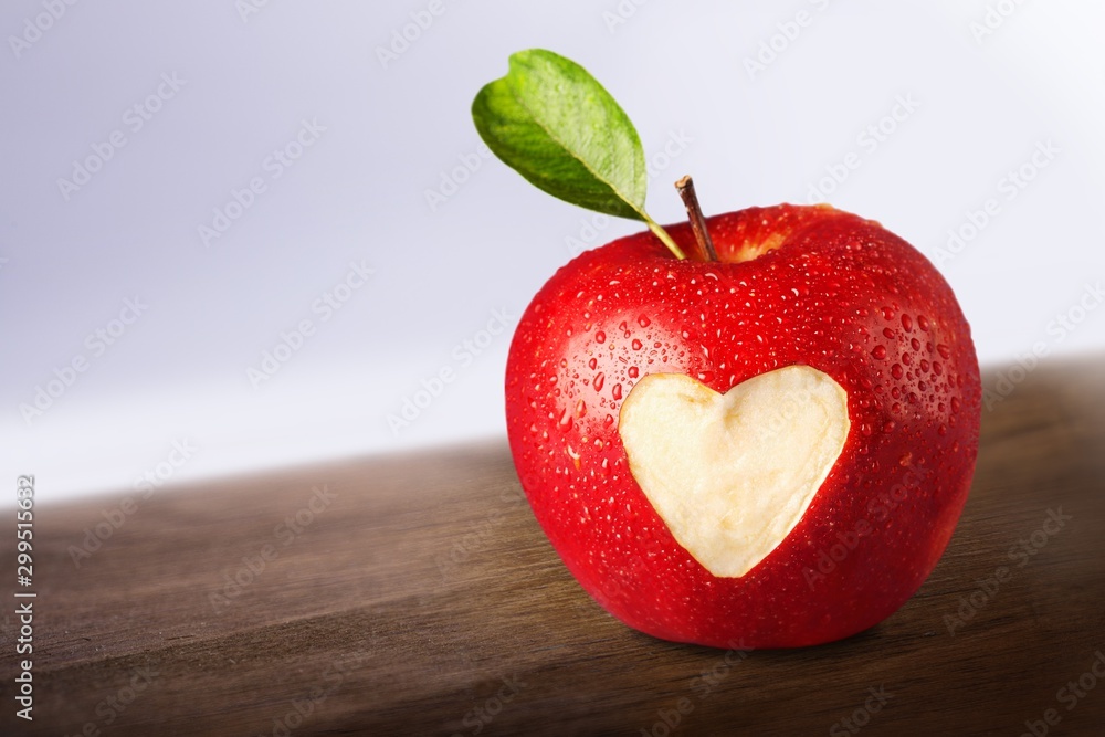 Apple with carved heart sign on light background