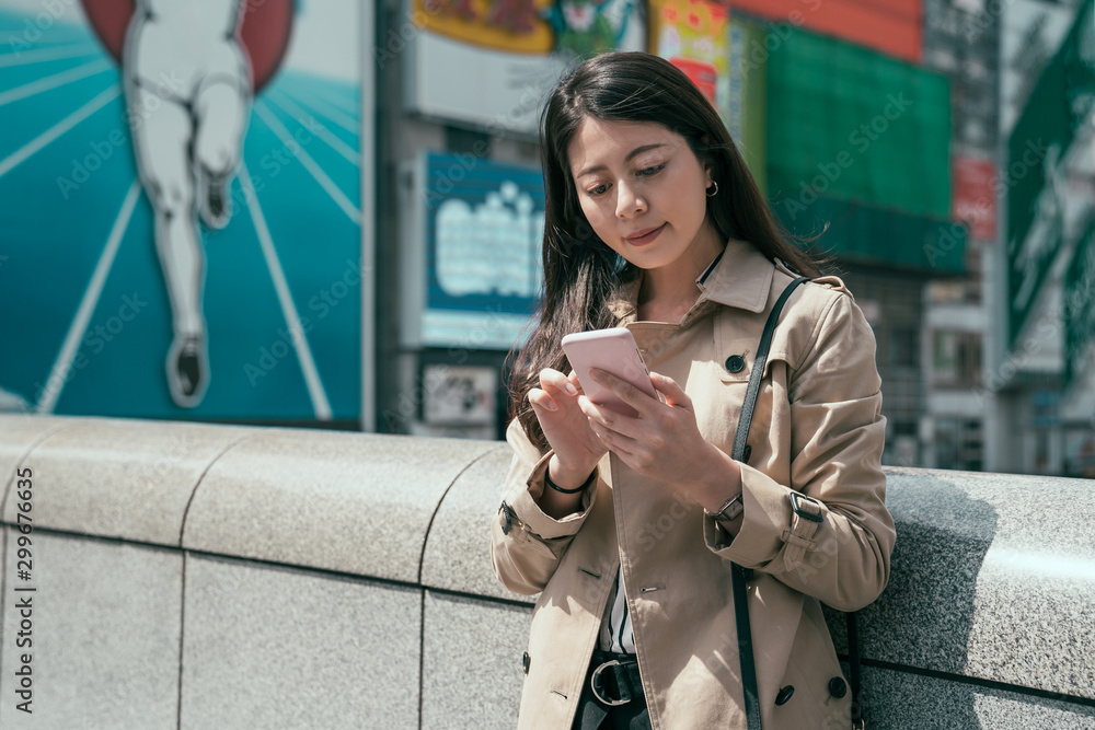 亚裔韩国女经理站在运河上方的桥上用手机在线发短信