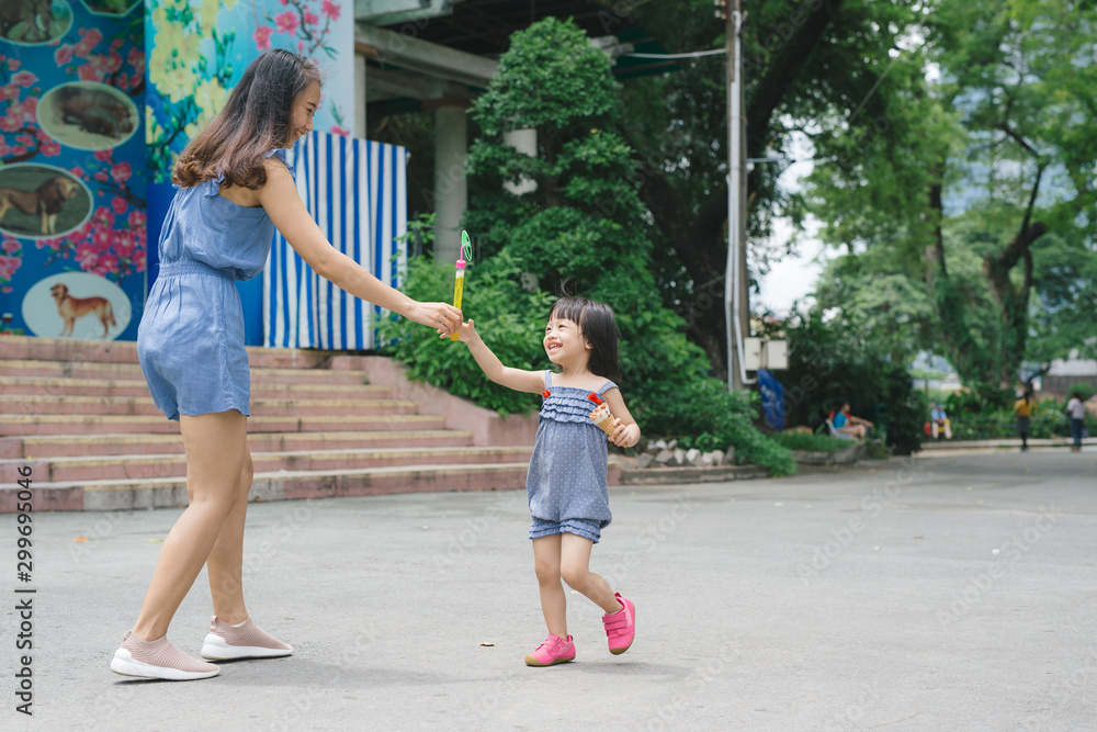 Mother and daughter playing and running around the park on beautiful morning.