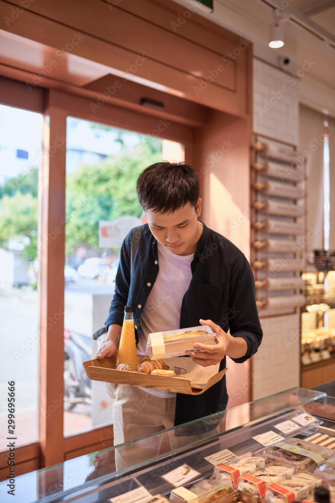 Handsome asian man buying bakery for coffee break in the afternoon. Bakery and Coffee break.