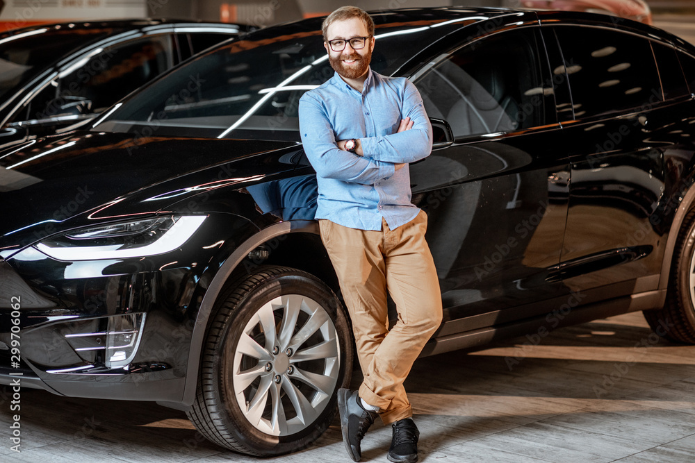 Portrait of a man near electric car at the showroom