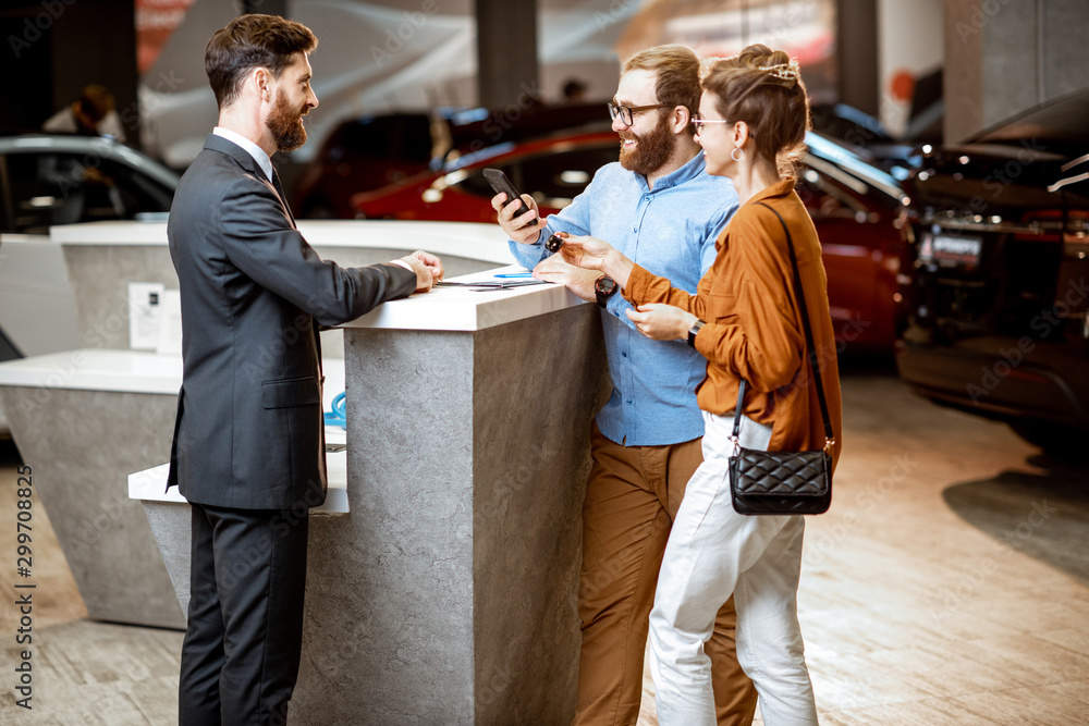 Sales manager with a young couple buying a new car