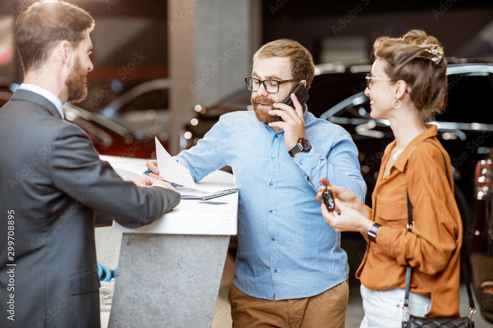 Sales manager with a young couple buying a new car