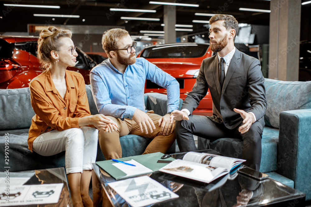 Young couple with saller on the couch at the car dealership