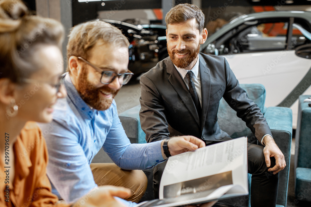 Couple with catalog and sales manager at the car dealership