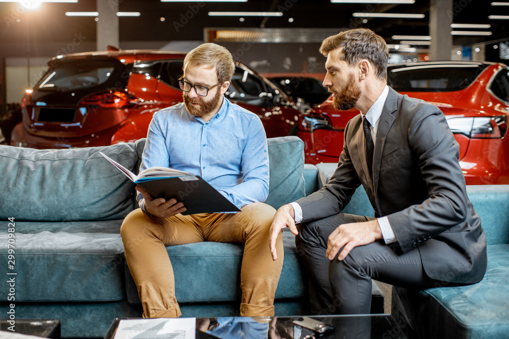 Man with sales manager on the couch at the car showroom