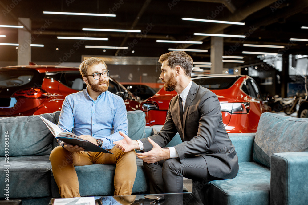 Man with sales manager on the couch at the car showroom