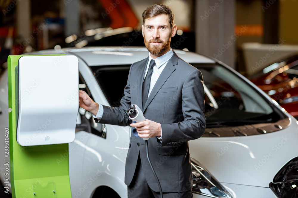 Salesman with electric car charging station in the dealership